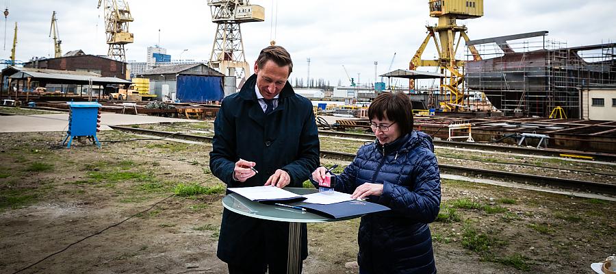 Marszałek Geblewicz i Beata Kordecka z firmy Finomar podpisują umowę na wsparcie branży stoczniowej.